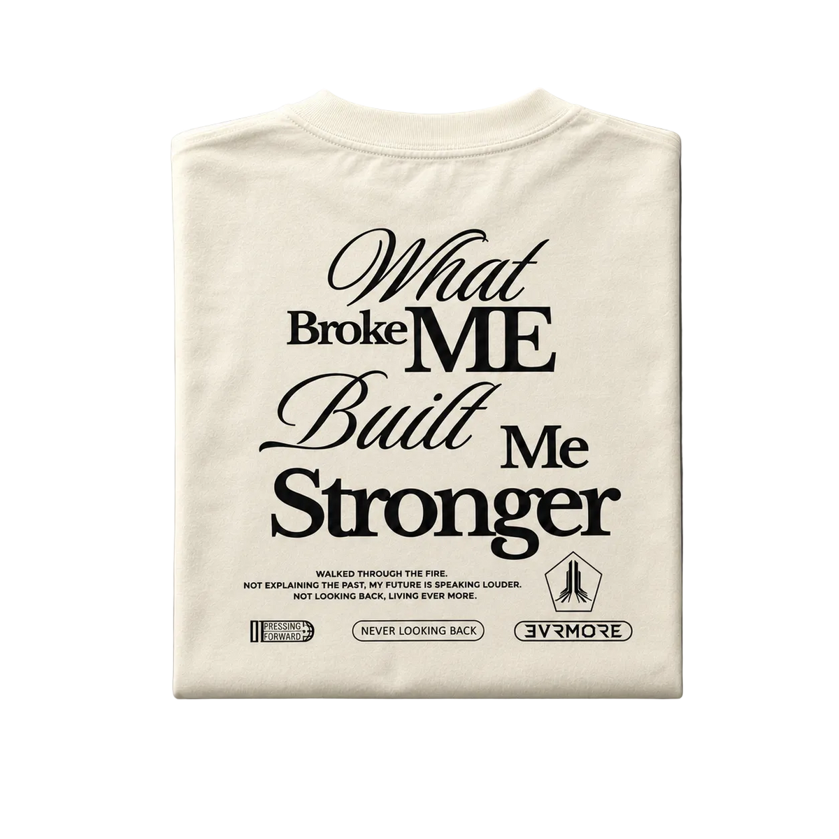 A folded off-white t-shirt with a black graphic text print reading 'What Broke ME Built Me Stronger' and smaller text below, displayed on a neutral gray background.