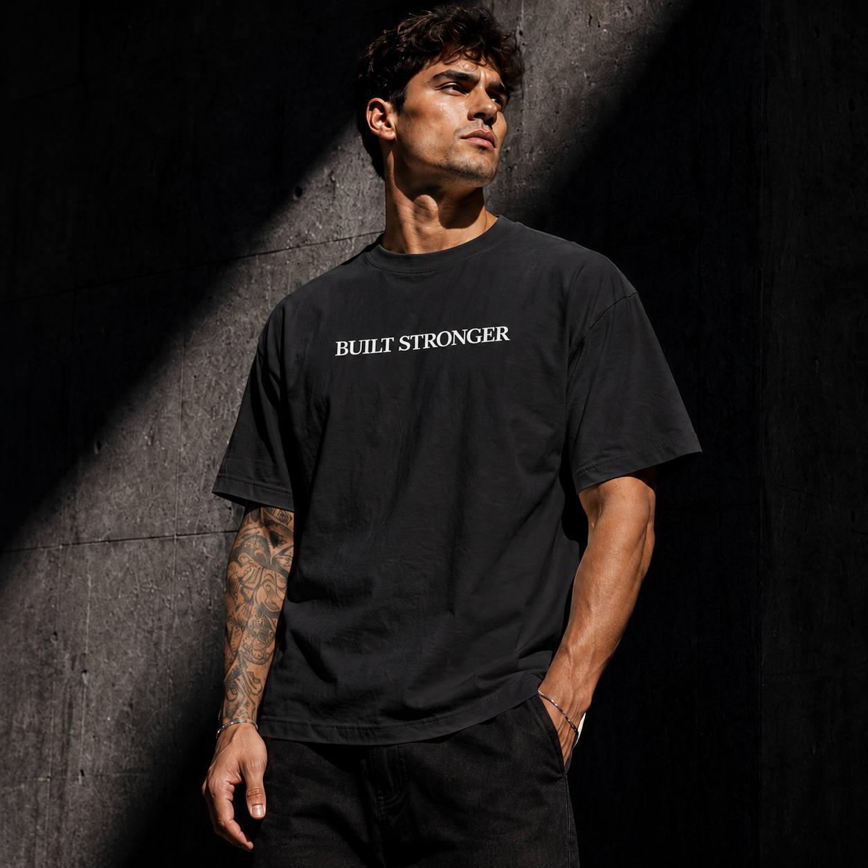 Man wearing a black t-shirt with 'BUILT STRONGER' text against a dark background