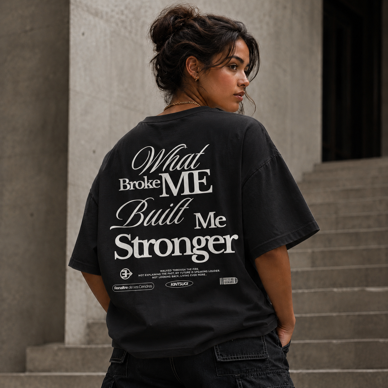 Person wearing a black t-shirt with motivational quote on the back, standing outdoors.