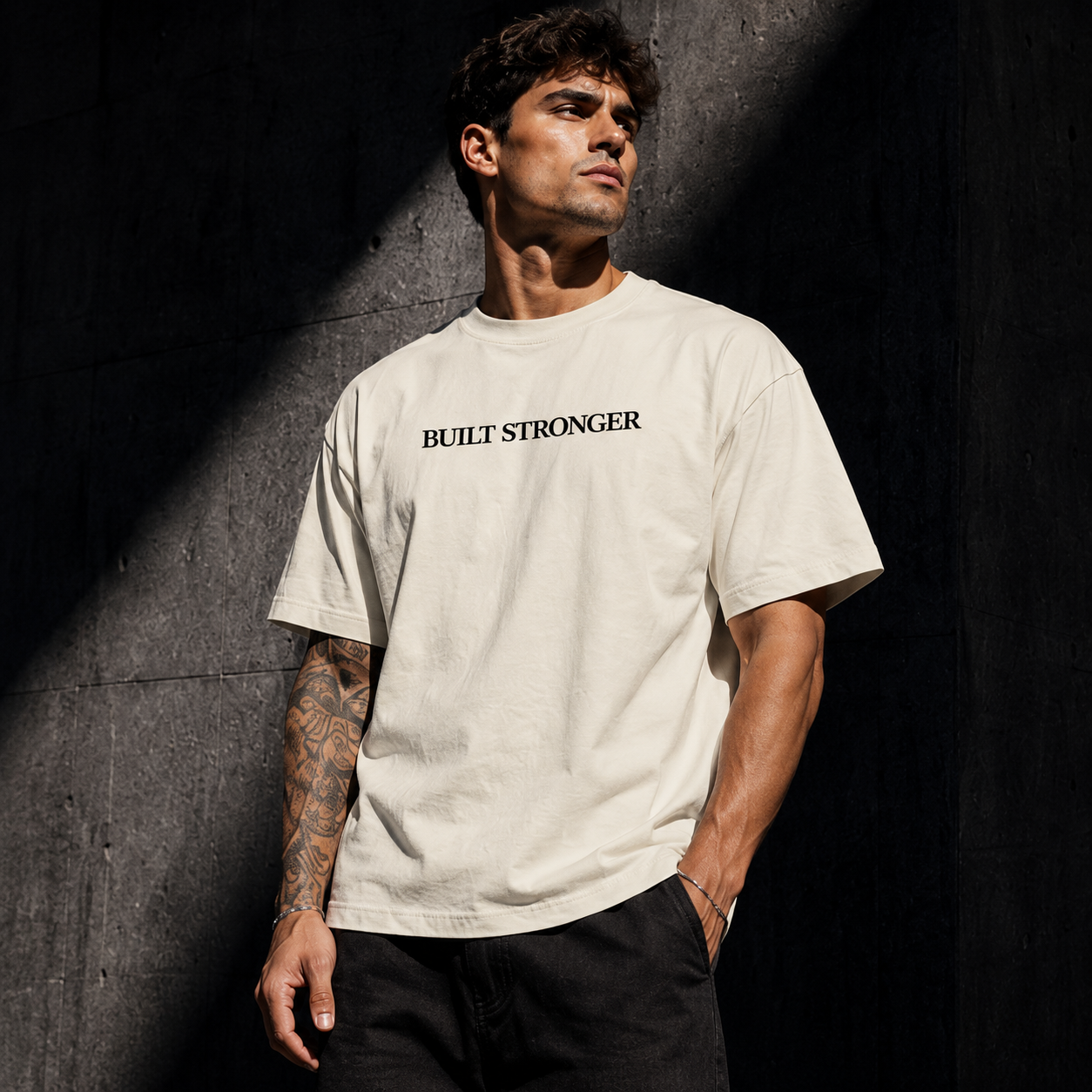 Man wearing a 'Built Stronger' t-shirt against a dark background