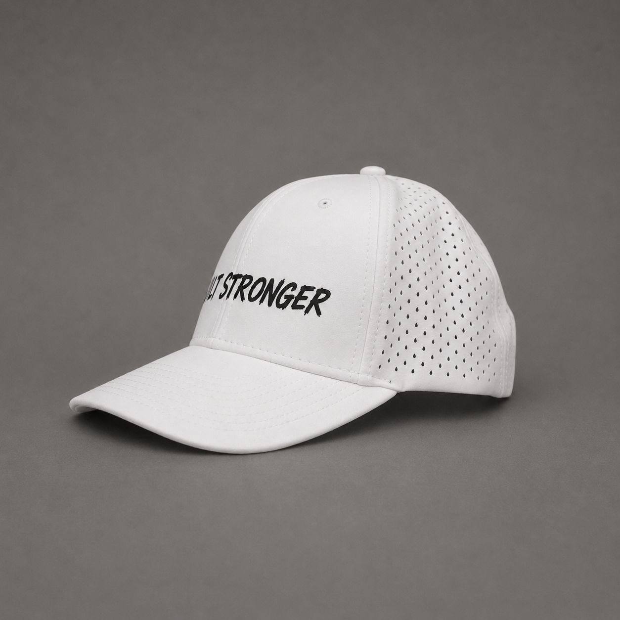 A white baseball cap with perforated back panels and black embroidered text reading 'JUST STRONGER' on the front, photographed on a neutral gray background.