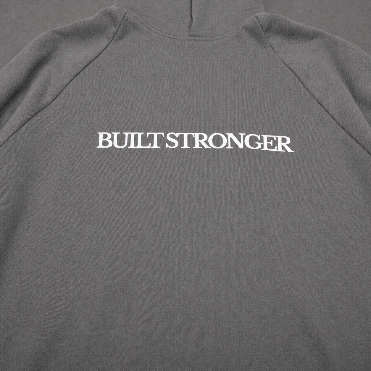 A close-up of a dark gray sweatshirt showing the back, with the words 'BUILT STRONGER' printed in white serif lettering across the upper back.